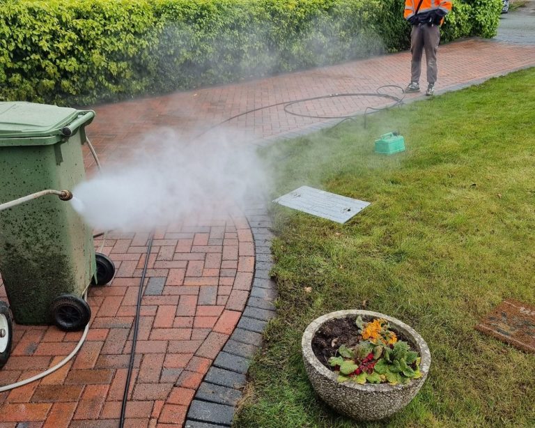 Man cleaning roof in a cherry picker A person on a platform uses a pressure washer to clean a roof.